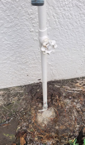 a broken residential water main sticking up out of the ground with a pool of water around it